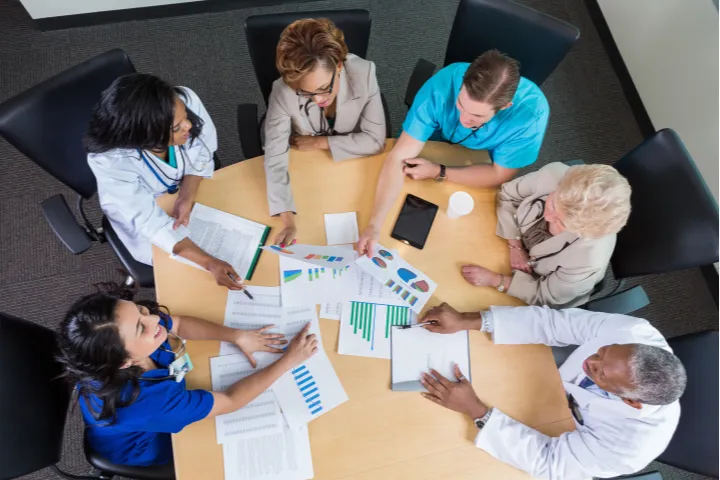 A birds eye view of a group of doctors and staff discussing important information.