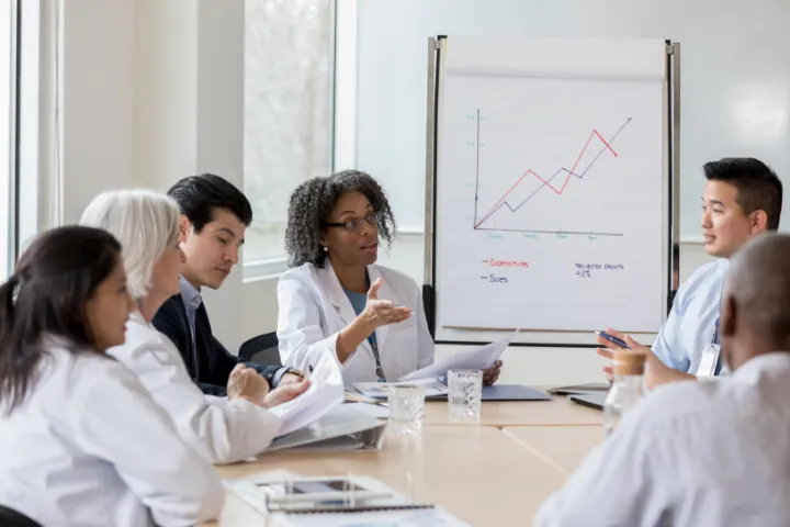 A group of doctors meeting at a table looking at a chart together